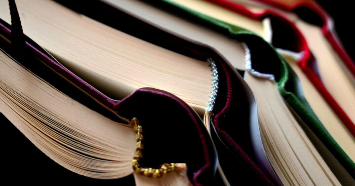 Pile of open hard cover books in jewel tones