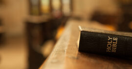 Black Bible laying on wooden table in church