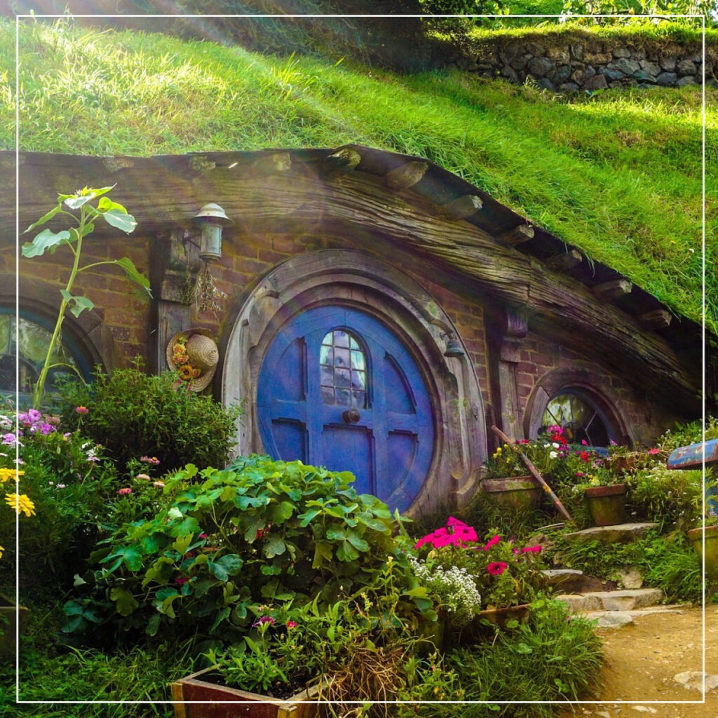 House built into a hill with grass on top and a round blue door