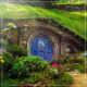 House built into a hill with grass on top and a round blue door