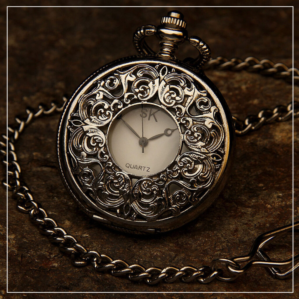 Ornate pocket watch and chain on a dark table
