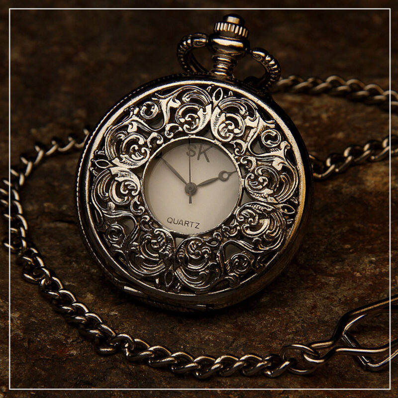 Ornate pocket watch and chain on a dark table
