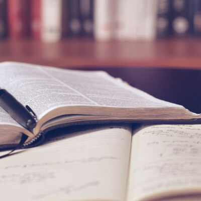Open Bible, notebook, and pen on table in home library