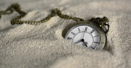 Pocket watch partially buried in sand