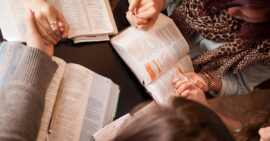 Group of women holding hands while studying the Bible and praying