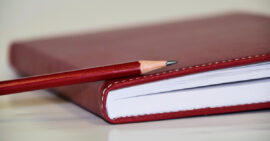 Red journal and red pencil on table