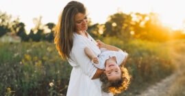 Loving Christian mother playing with son outdoors as sun sets