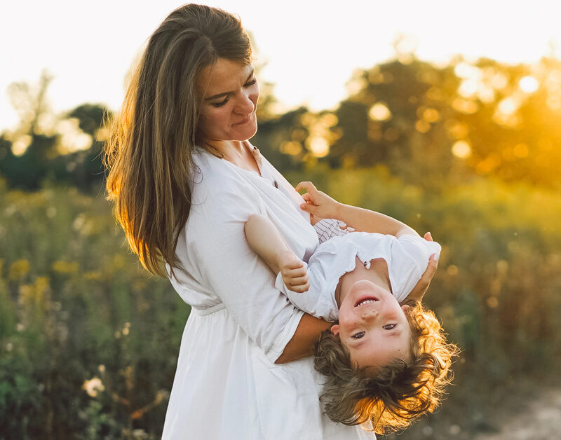 Loving Christian mother playing with son outdoors as sun sets