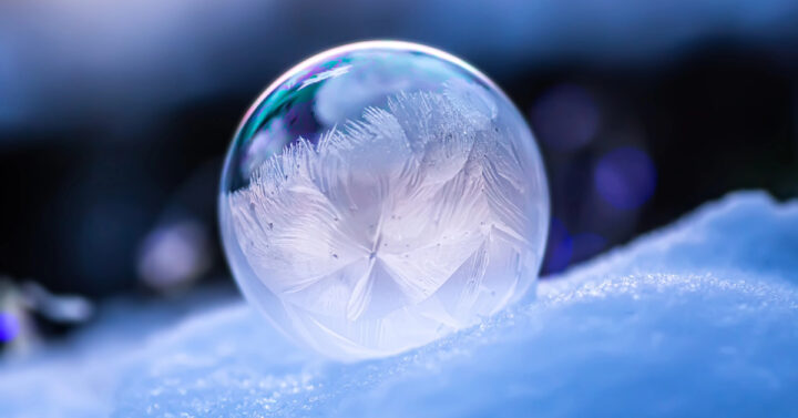 Frozen bubble with frost pattern sitting on top of snow