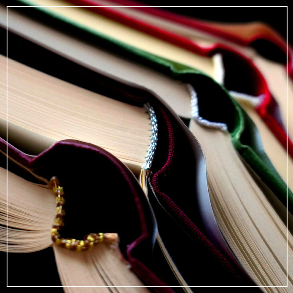 Pile of open hard cover books in jewel tones