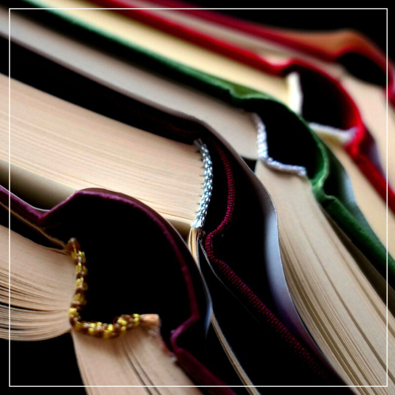 Pile of open hard cover books in jewel tones