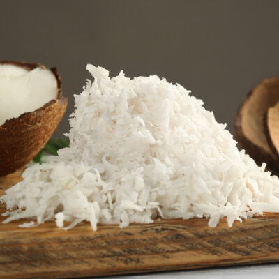 Coconuts and shredded coconut on a wooden cutting board