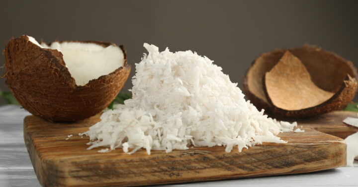 Coconuts and shredded coconut on a wooden cutting board