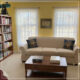 Lace curtains on two windows with a couch and coffee table in front of them