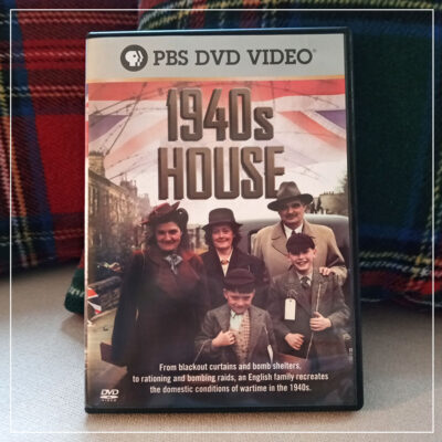 Copy of 1940s House DVD on couch with plaid pillows behind it