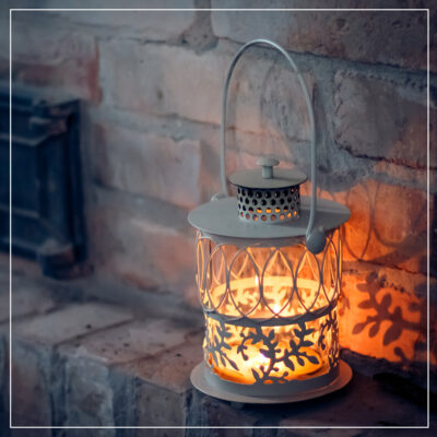 Candle lantern on brick fireplace shelf