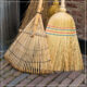 Broom, wooden rake, metal trash can on brick floor