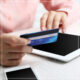 Woman in pink sweater entering credit card info into tablet
