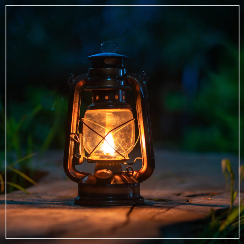 Lit oil lanterns on a slate walk in the garden