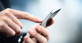 Man's hands dialing on a silver smart phone