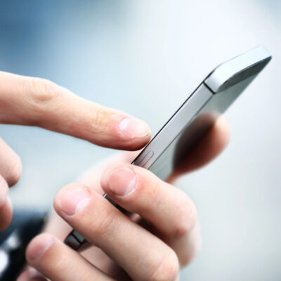 Man's hands dialing on a silver smart phone