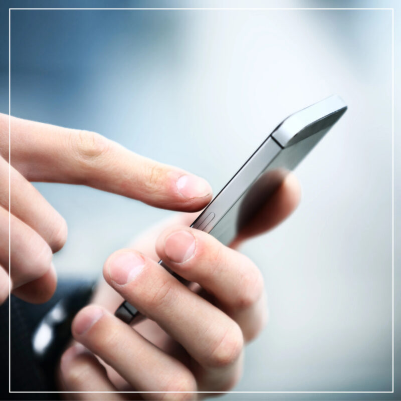 Man's hands dialing on a silver smart phone