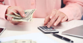 Women in pink sweater counting money and using calculator