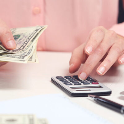 Women in pink sweater counting money and using calculator