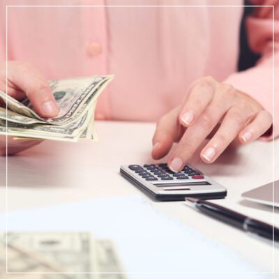 Women in pink sweater counting money and using calculator