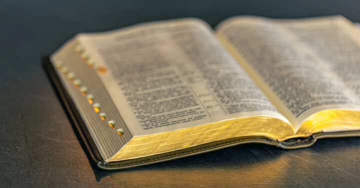 Open Bible with black cover and gold gilt edges on table