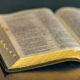 Open Bible with black cover and gold gilt edges on table