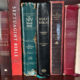 Shelf of Bibles including KJV, NIV, ESV, NASB, The Geneva Bible, Scofield Bible, and Study Bibles